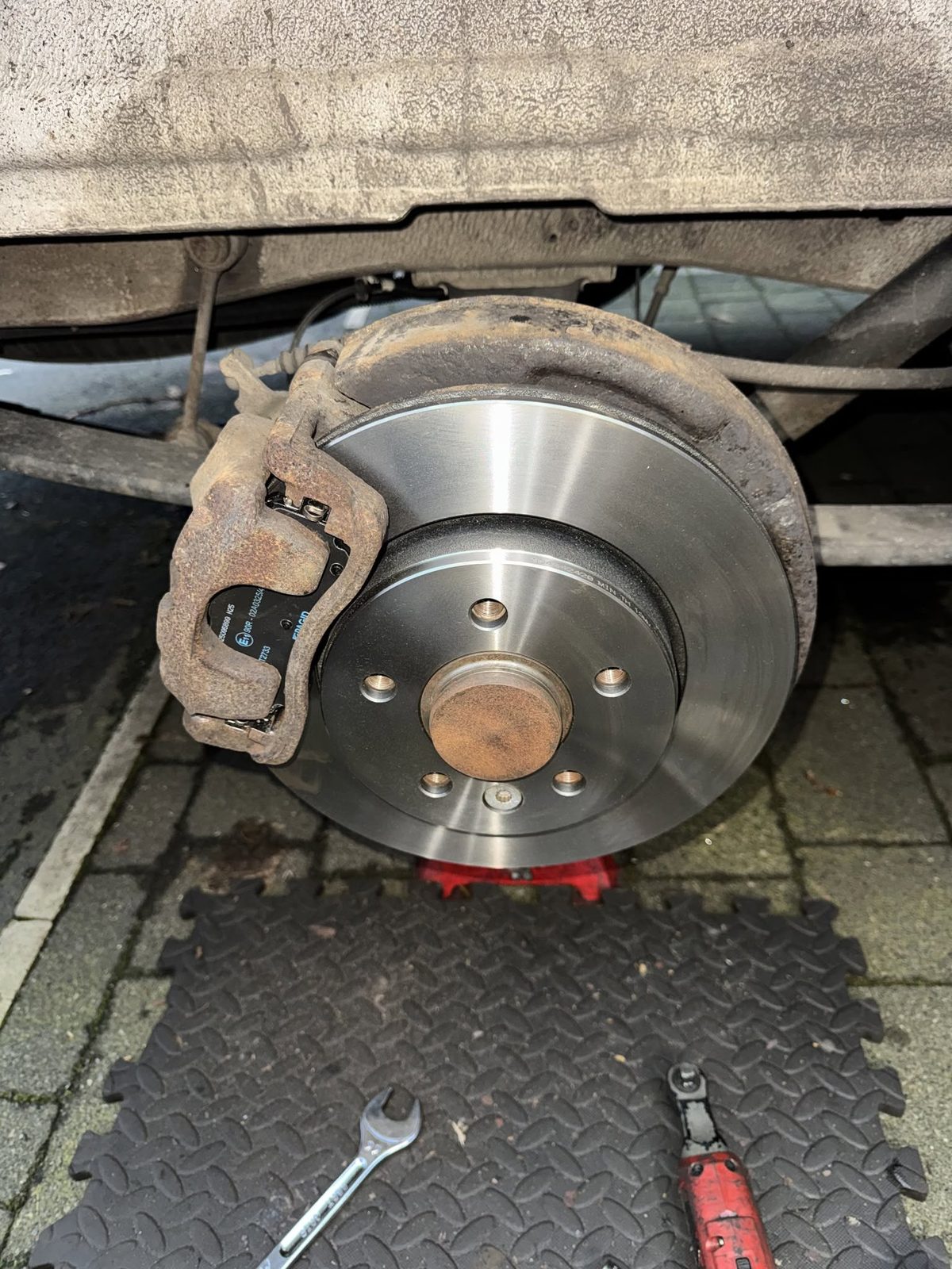 New brake disc and pads fitted on a driveway during a mobile brake service